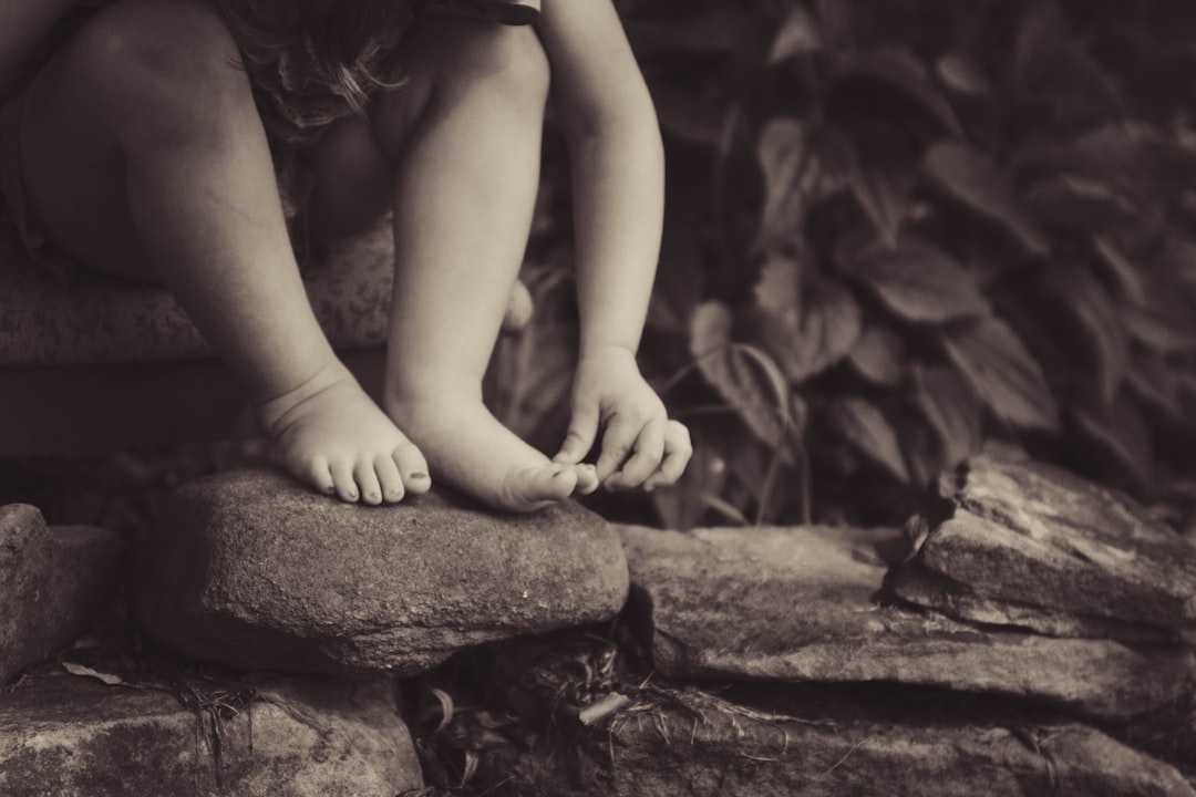 depth-photography-of-child-sitting-on-rock-beside-plant-v-p36e5olj0